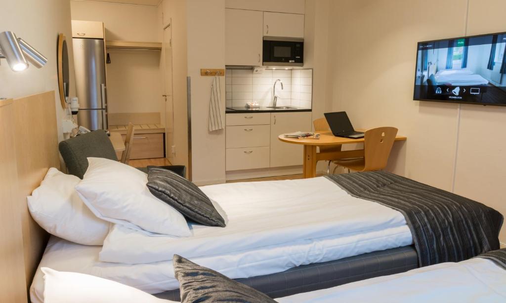 um quarto com uma cama e uma cozinha com uma televisão em Linköpings Cityhotell och Vandrarhem em Linköping