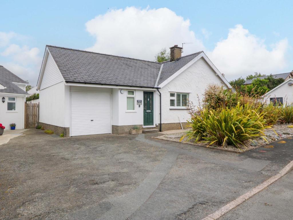 a white house with a driveway at 5 Ger Afon in Pwllheli