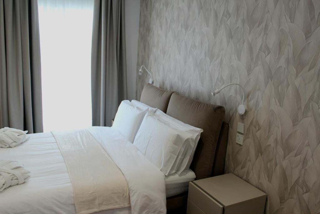 a bedroom with a bed with white sheets and a window at Balzanija Boutique Accommodation in Balzan
