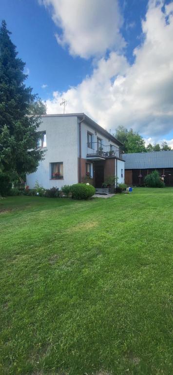 a house with a large yard with a green field at Pokoje u Irenki in Augustów