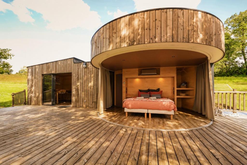 a circular house with a bed on a deck at LES 2 CABANES in Labastide-Gabausse
