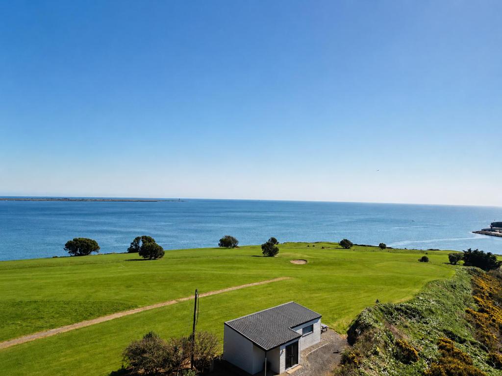 a house on a hill next to the ocean at Dunmore East Ocean View Suite in Dunmore East
