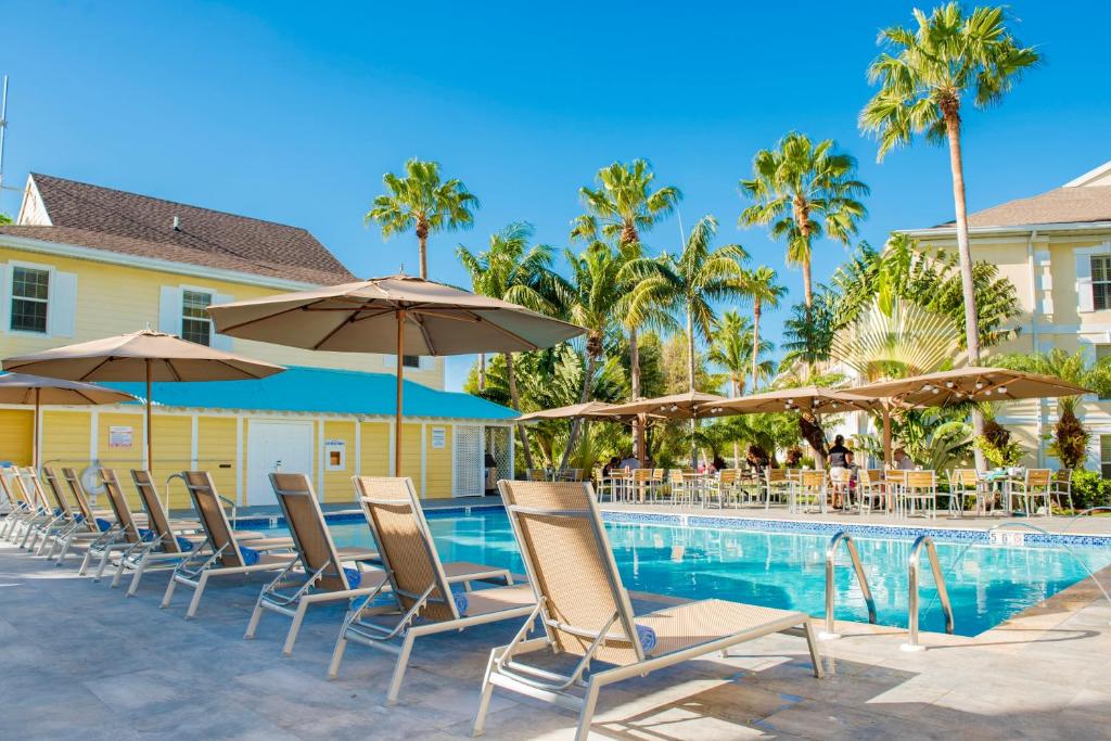 a row of chairs and umbrellas next to a swimming pool at Sunshine Suites Resort in George Town