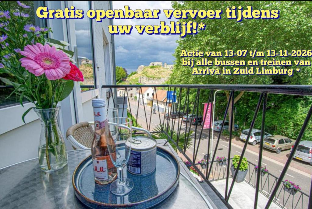 a glass table with a bottle and a vase on a balcony at Logement viphouse Valkenburg in Valkenburg