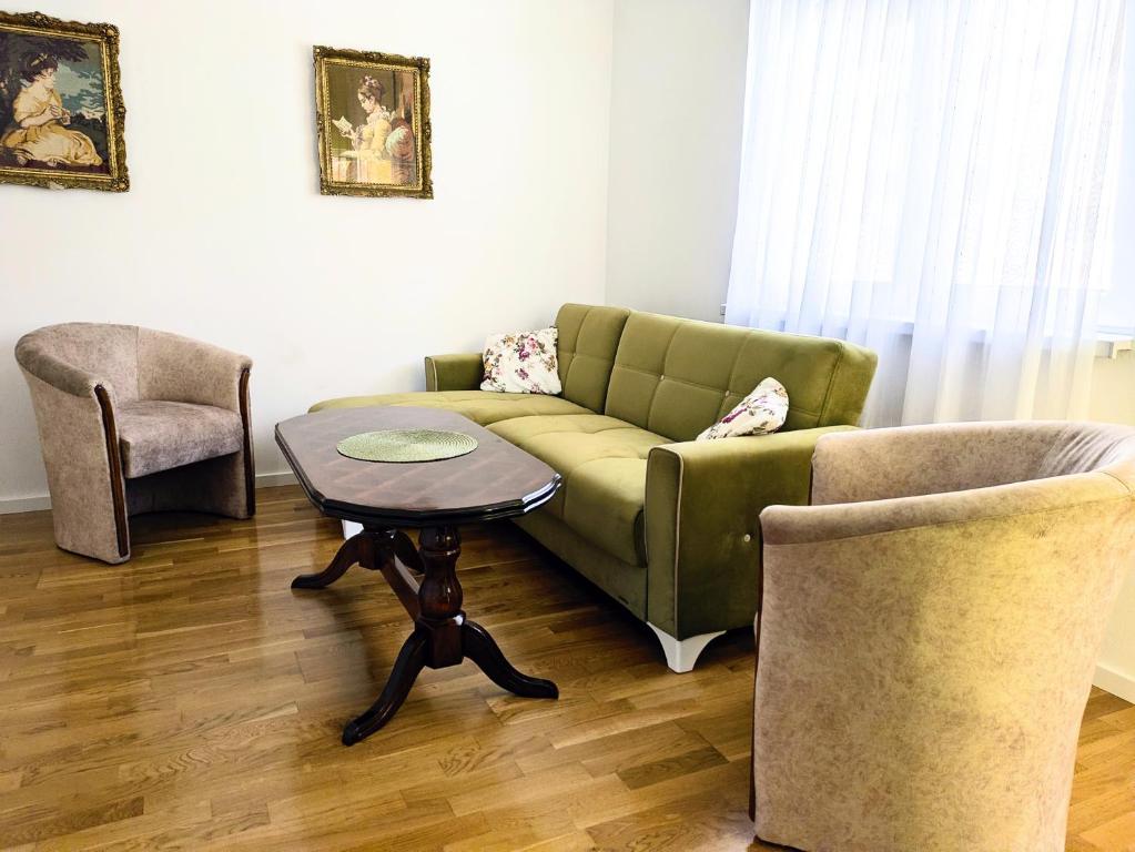 ein Wohnzimmer mit einer grünen Couch und einem Tisch in der Unterkunft Nirvana Apartman in Brčko
