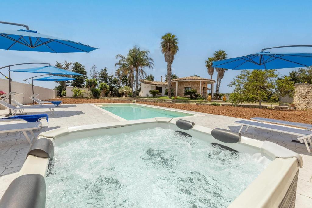 a hot tub with two chairs and umbrellas at Villa Cassandra in Alliste