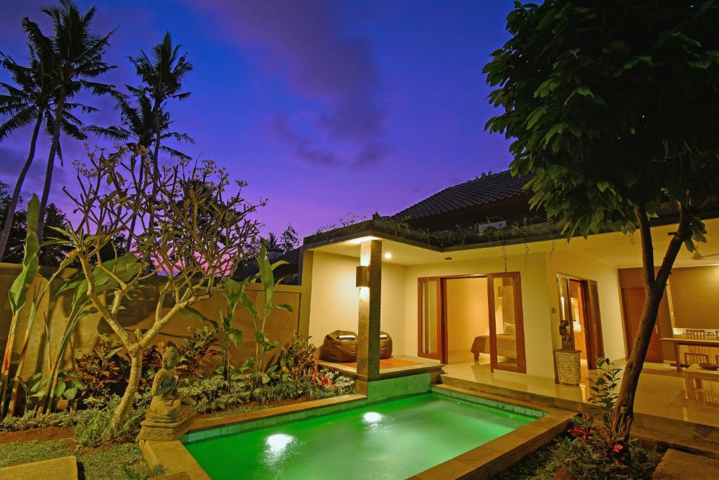 a villa with a swimming pool in front of a house at Villa Padma Ubud in Ubud