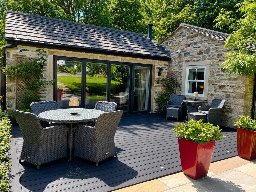 a patio with a table and chairs on a deck at The Summerhouse in Keighley