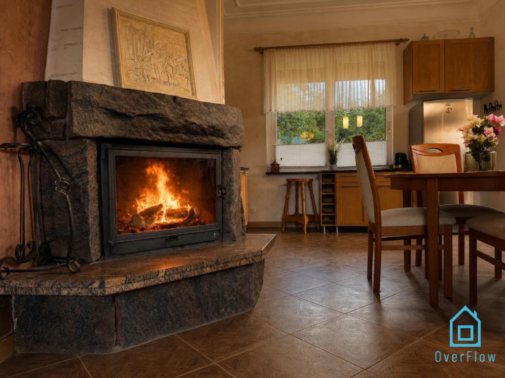 a fireplace in a living room with a kitchen at NaWypasie Grand Apartment with Fireplace Beautiful Garden SUP Board and Just 30 Minutes from Gdańsk and Gdynia in Szemud