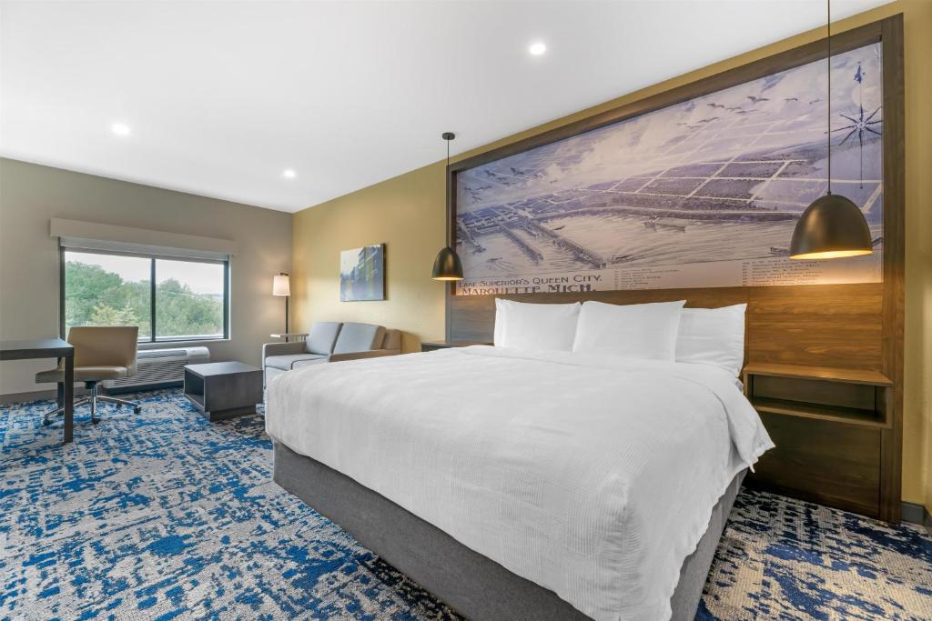 a hotel room with a large bed and a desk at Best Western Plus Marquette Hotel & Suites in Marquette