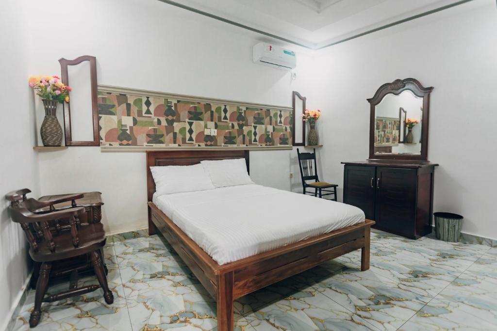 ein Schlafzimmer mit einem Bett, einem Schreibtisch und einem Spiegel in der Unterkunft La clémentine in Jacqueville