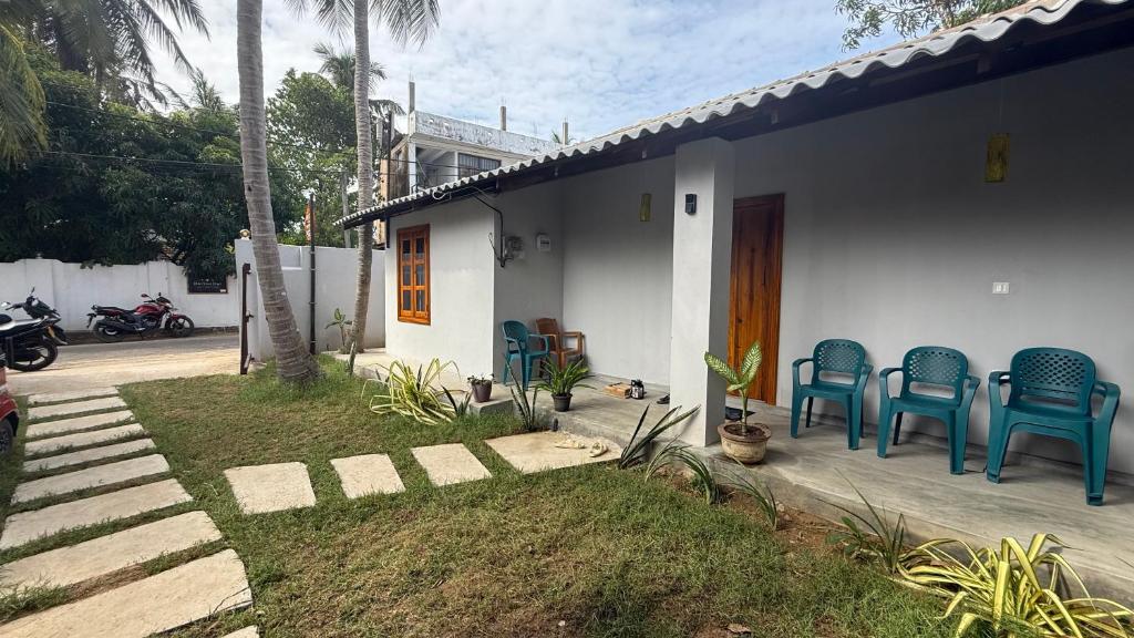 a house with blue chairs sitting on a porch at Holabay Surf Hostel in Arugam Bay
