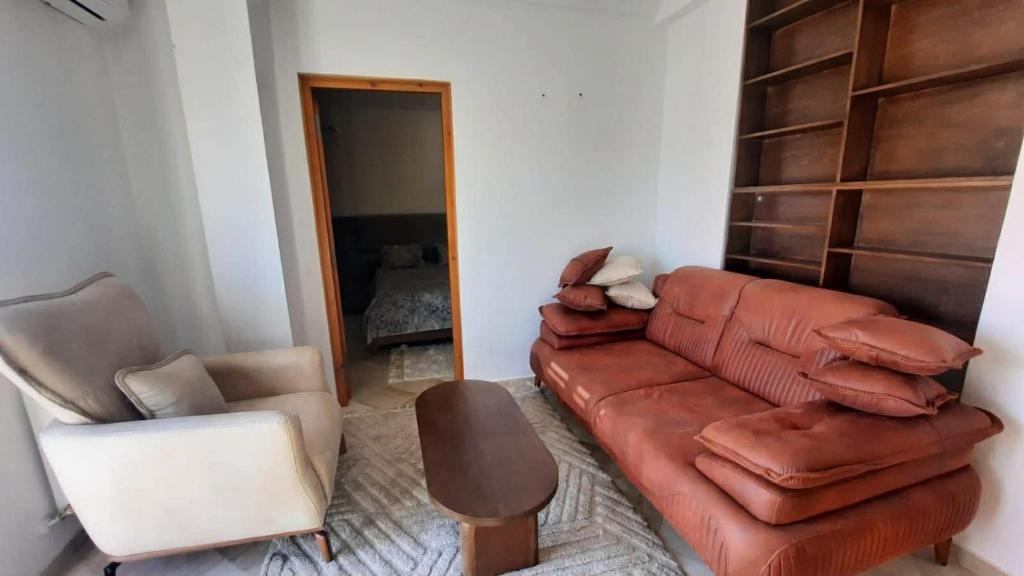 a living room with a brown leather couch and two chairs at Fantastic appartement in Hammam Sousse