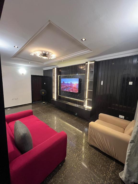 a living room with a red couch and a flat screen tv at Seyi Homes in Hausa