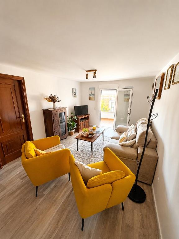 a living room with two yellow chairs and a couch at Apartamento As Caldelas in O Grove