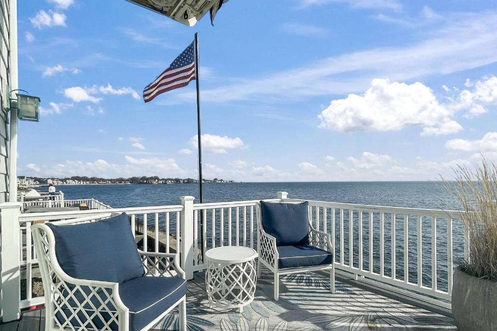 a balcony with two chairs and an american flag at Sunrise Waterfront Retreat in Milford