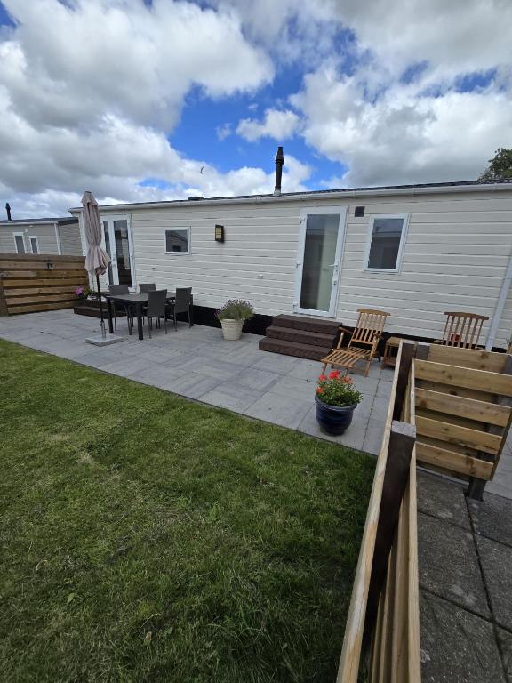 a trailer with a patio with a table and chairs at Prachtig chalet DE WADLOPER in Westerland