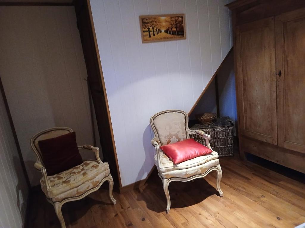 a room with two chairs and a red pillow at gite du coin in Cunlhat
