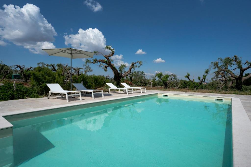 a swimming pool with two chairs and an umbrella at Oltre i coni in Santa Lucia