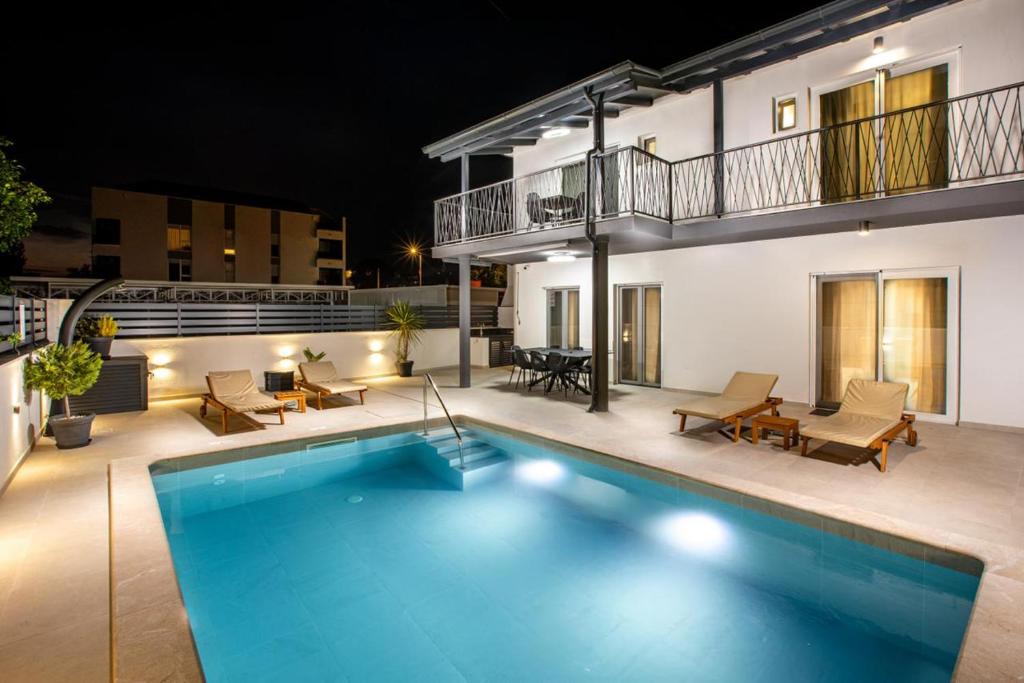 a swimming pool in front of a house at night at Villa Luce in Podstrana