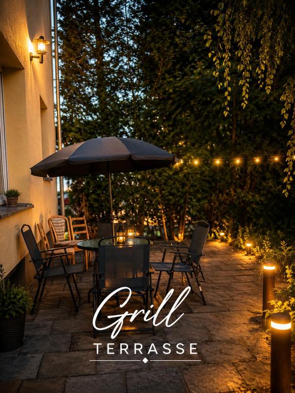 a patio with a table with an umbrella and lights at Pension Jasmin B in Chemnitz