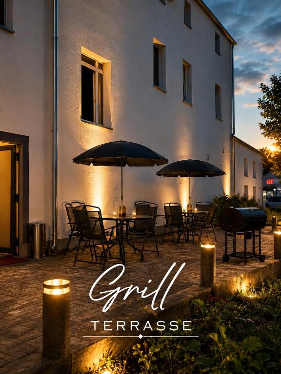 a group of tables with umbrellas in front of a building at Pension Jasmin A in Chemnitz