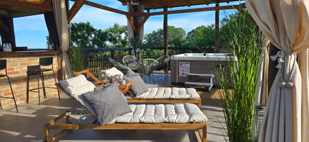 a screened in porch with benches and pillows at Studio apartman King with private jacuzzi and sauna in Štakorovec