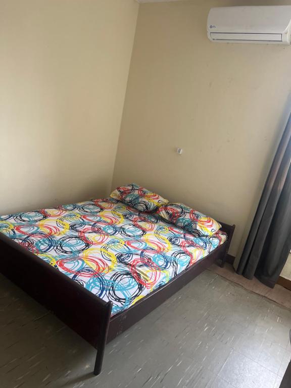 a bed with a colorful comforter in a room at Colonial Appart Boss in Bouaké