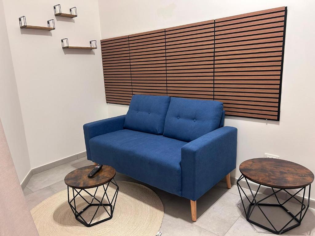 a blue couch sitting in a room with two tables at Venera Rooms in Caltanissetta