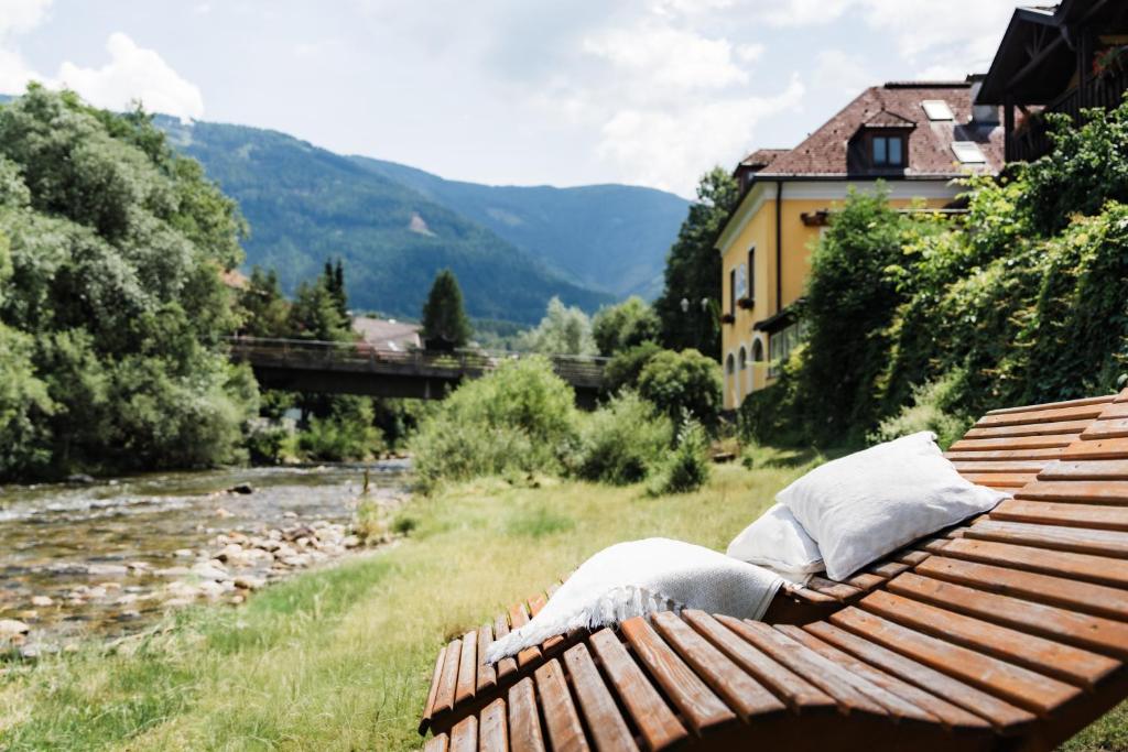 a wooden bench sitting next to a river at Hotel Restaurant Platzer in Gmünd in Kärnten