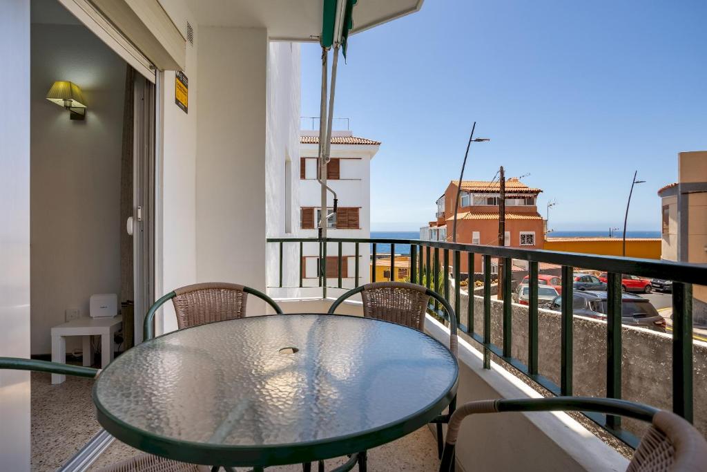 a glass table on a balcony with a view of a street at Home2Book Sunny Terrace Apt, el Rincón de ManFe in Candelaria