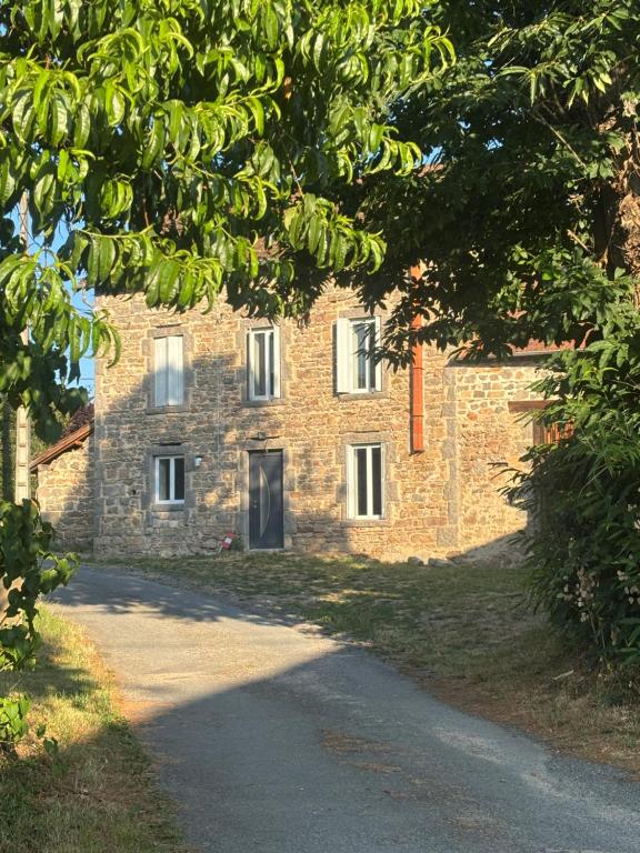 a stone building with a road in front of it at Gîte de Fumouse in Le Mayet-de-Montagne