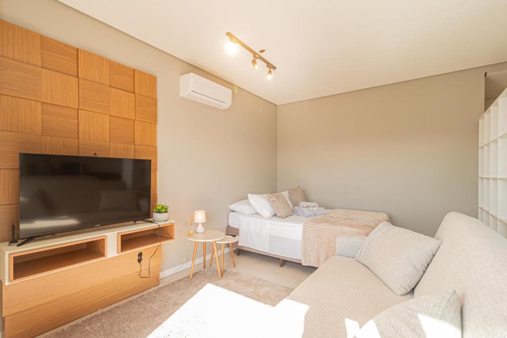 a living room with a bed and a flat screen tv at Loft Centralíssimo com Garagem in Pelotas