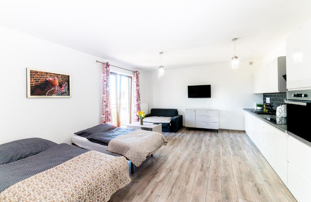 a white room with a bed and a kitchen at Central Apartments Premium in Goleniów