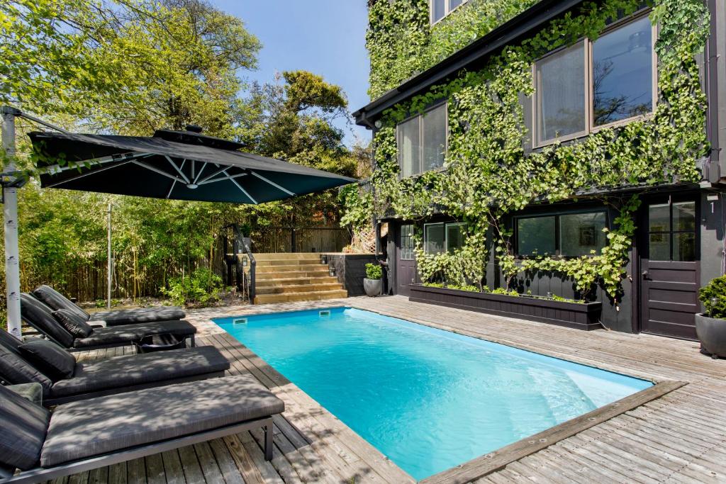 a swimming pool with chairs and an umbrella next to a house at The Pines Men-Only Stay in Fire Island Pines