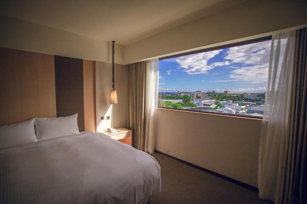 a hotel room with a bed and a large window at Inn by the Village in Taitung City