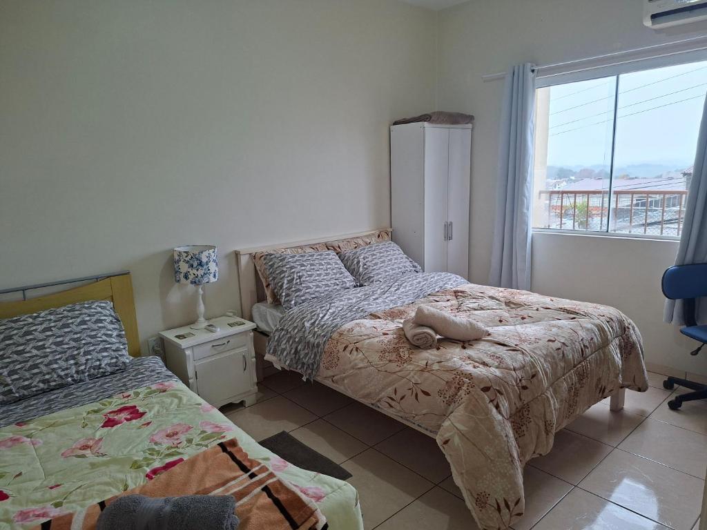 a bedroom with two beds and a window at Apart próximo a Unimed, Catedral e HSA com 2 quartos com 2 ARES e garagem in Santo Ângelo