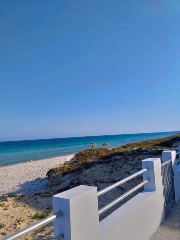 a white bench on a beach near the ocean at Maison front de mer 2 in Kelibia