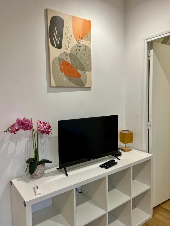 a flat screen tv sitting on top of a white cabinet at Chemin de fer adorable appartement in Gagny