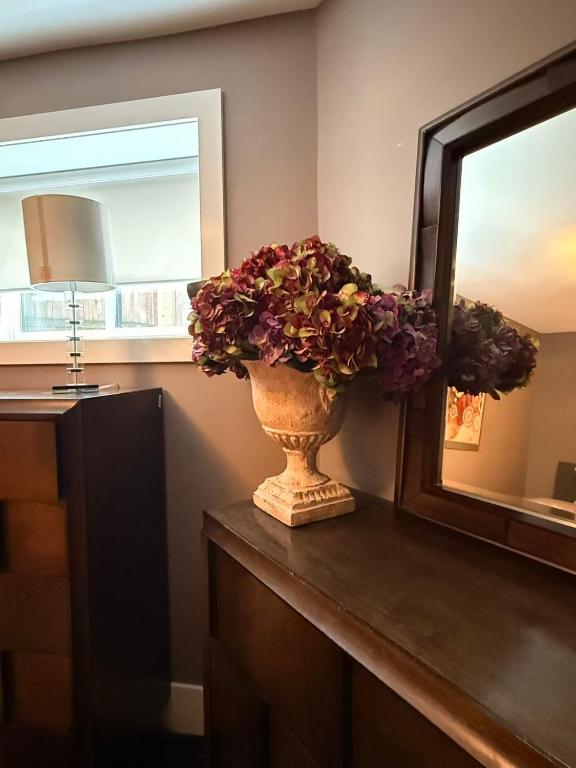 a vase with flowers on a counter next to a mirror at White Rock Joy Inn in White Rock