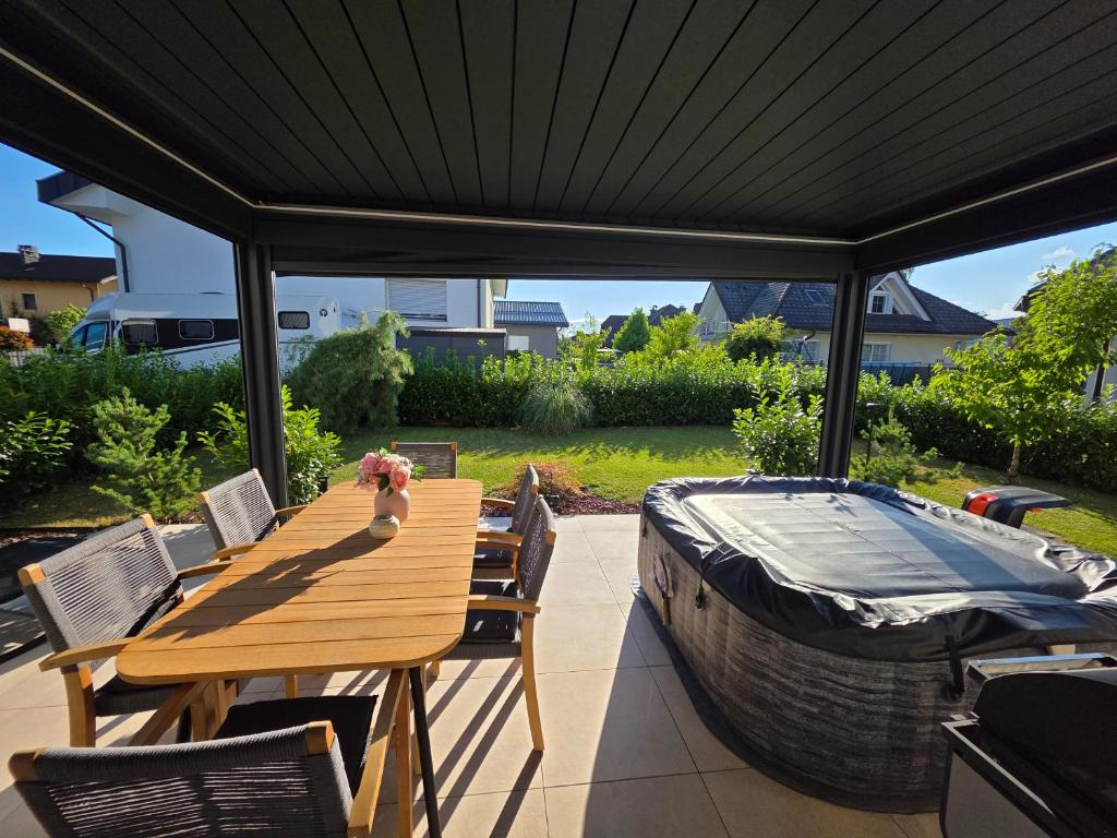 a deck with a wooden table and a bath tub at Private House with Jacuzzi and Sauna in Domžale