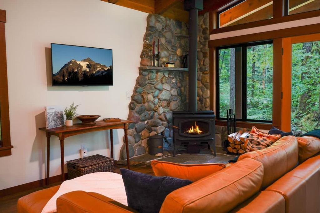 a living room with a couch and a stone fireplace at Elysian at Mount Baker in Glacier