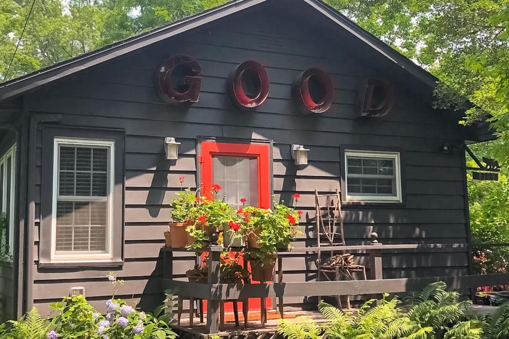 a black house with a red door and flowers at Steps to Beach & Lake Michigan! Family Retreat in Turner Shores