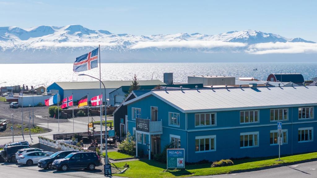 a blue building with a flag and mountains in the background at Hótel Húsavík in Húsavík