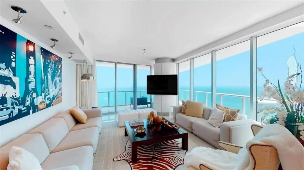 a living room with white furniture and large windows at Jade Beach Escape in Sunny Isles Beach