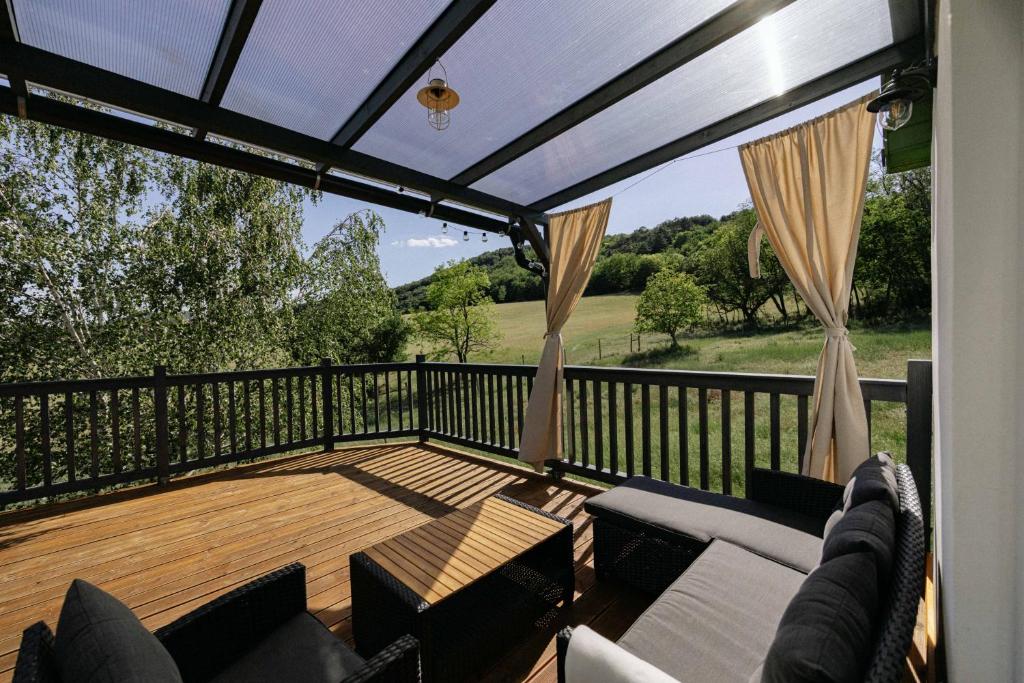 a screened in deck with a couch and chairs at Cserháti Házikó in Alsótold