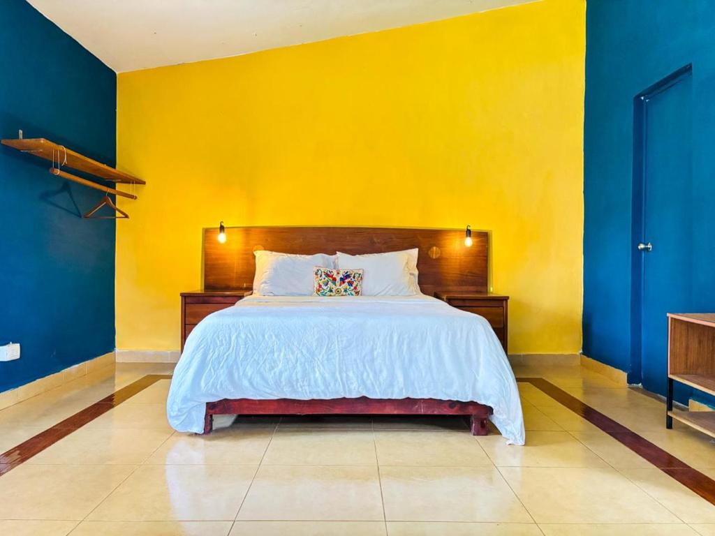 a bedroom with a large bed with a yellow wall at Loft Bugambilia en Casa Viva Merida in Techoh