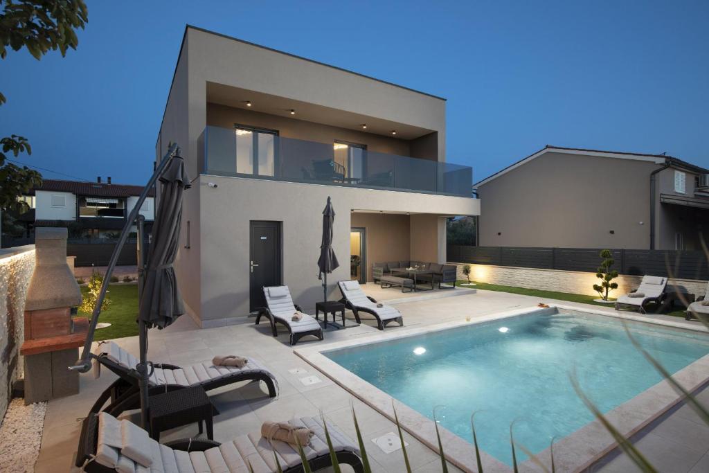 a house with a swimming pool in front of it at Villa Del Sol near Fažana in Valbandon