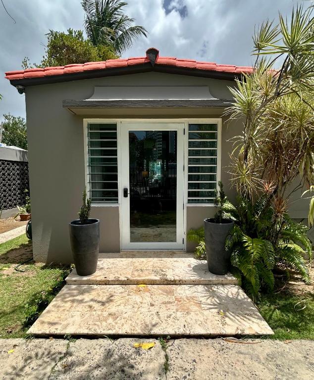 a small house with a door and palm trees at Isla Verde By The Beach Guest House in San Juan