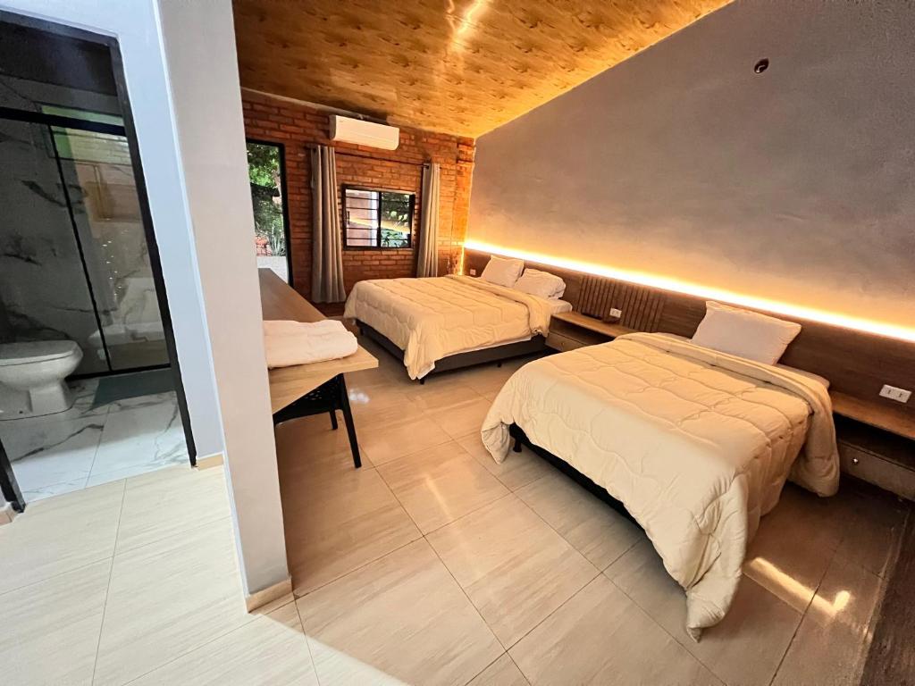 ein Zimmer mit zwei Betten und einem Badezimmer in der Unterkunft Hotel Suites Bambú in Minga Guazú